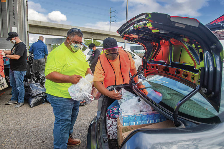 DENNIS ODA / DODA@STARADVERTISER.COM
                                Joe Teixeira, left, and Leon Barber loaded bags of prepackaged food boxes and other items. Volunteers distributed 2,000 boxes of fresh produce, meats, keiki snacks and more while supplies lasted.