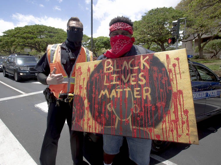 DENNIS ODA / DODA@STARADVERTISER.COM
                                The Black Lives Matter march started at Ala Moana Park to the state Capitol on Oahu. As the protesters marched past South Street, Jeremy McClamp paused next to a police officer who flashed a shaka sign.