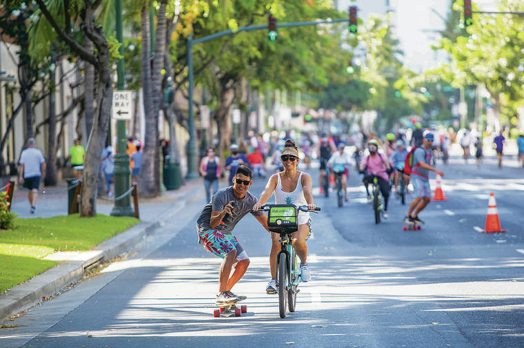 DENNIS ODA / DODA@STARADVERTISER.COM
                                Keoni Ching, above left, took a video Sunday of himself being towed by Jes Schlais during the first Kalakaua Open Street Sunday on Kalakaua Avenue. Vehicular traffic was closed between Seaside and Kapahulu avenues from 6 a.m. to noon.