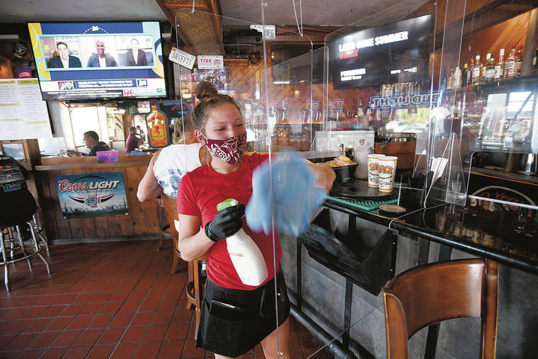 BRUCE ASATO / BASATO@STARADVERTISER.COM
                                Brittany Ciscato, bartender and server at The Shack Kailua, sanitizes plexiglass dividers installed at the bar. The Shack has moved some tables outside to expand capacity while accommodating social distancing.
