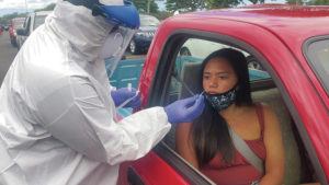 CRAIG T. KOJIMA / CKOJIMA@STARADVERTISER.COM
                                Drive-thru COVID-19 testing was held Saturday at Waipio Peninsula Soccer Complex. Technician Kaipo Lindsey administered a test to Aina Iglesias, who has been working at the Hilton Doubletree Alana for two years.