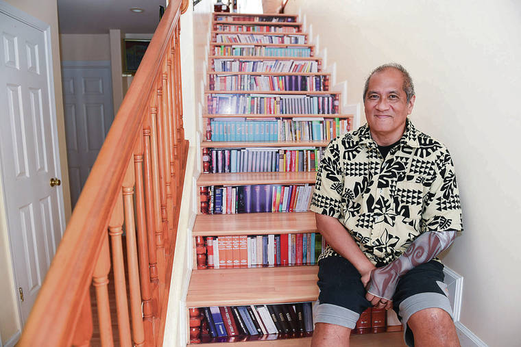 BRUCE ASATO / BASATO@STARADVERTISER.COM
                                Dr. Lucio Pascua fell ill with the coronavirus in March after a trip to New Jersey and New York. He was on a ventilator for 10 days before finally recovering. Pascua sits on his stairway with books stored behind.