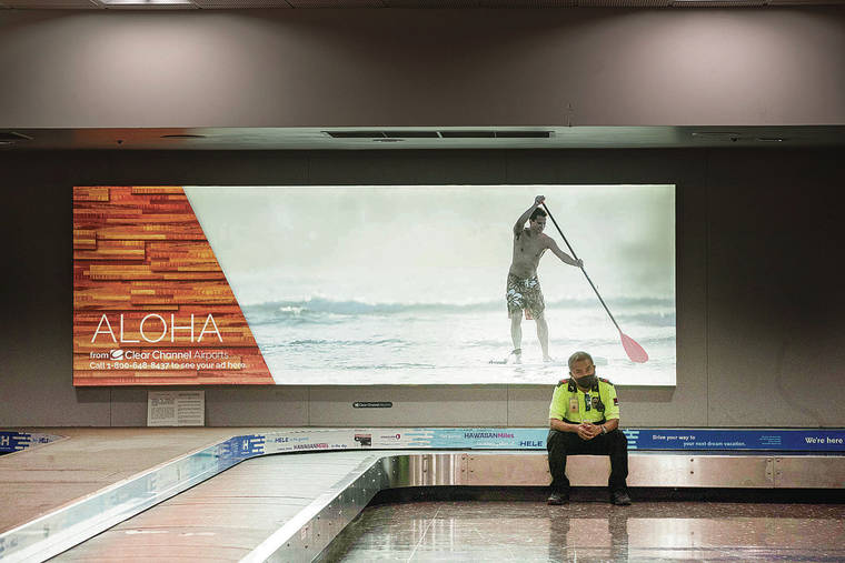 CINDY ELLEN RUSSELL / CRUSSELL@STARADVERTISER.COM 
                                Interisland quarantine travel restrictions were lifted for passengers Tuesday. A security guard took a break on an empty baggage carousel as travel was still light at Daniel K. Inouye International Airport.