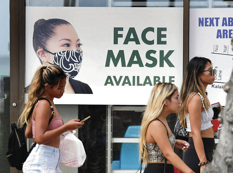 BRUCE ASATO / BASATO@STARADVERTISER.COM
                                Pedestrians on Thursday walked by a sign on the window of an ABC Store on a Kalakaua Avenue sidewalk that announces that face masks are available.