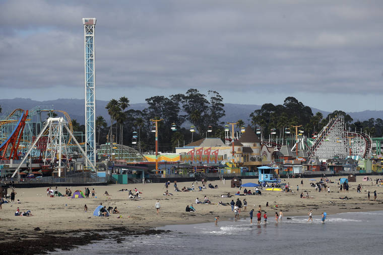 ASSOCIATED PRESS / JULY 2
                                People visit a beach in front of the Santa Cruz Beach Boardwalk during the coronavirus outbreak in Santa Cruz, Calif. Californians are being wooed by local tourism boards promising safe and clean lodging, dining and sightseeing in a bid to boost the state’s devastated economy. Visitors bureaus in Sonoma, Santa Cruz, Monterey and greater Palm Springs are among those pitching local travel with messages to wear masks and to practice social distancing.