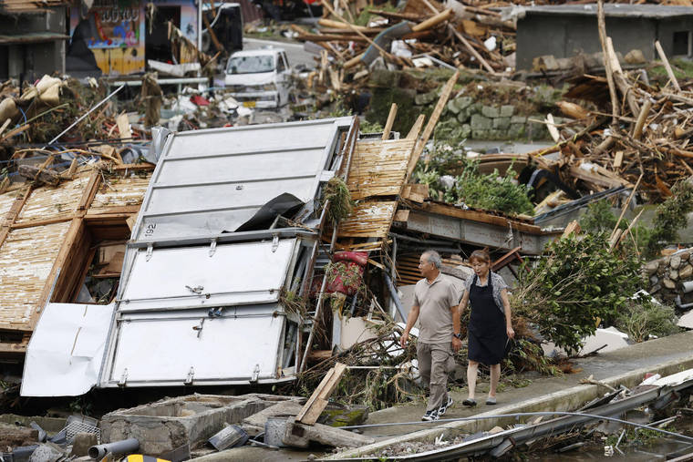 KYODO NEWS VIA ASSOCIATED PRESS
                                A couple walked near debris from heavy rain in Kumamura, Kumamoto prefecture, southern Japan on Monday. Rescue operations continued and rain threatened wider areas of the main island of Kyushu.