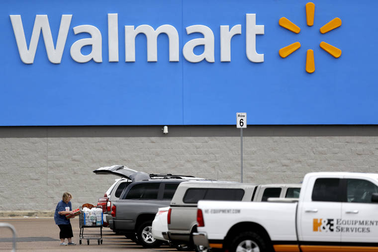 ASSOCIATED PRESS
                                A woman pulled groceries from a cart, March 31, to her vehicle outside of a Walmart store in Pearl, Miss. Walmart will require customers to wear face coverings at all of its namesake and Sam’s Club stores.