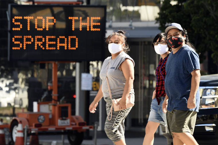 ASSOCIATED PRESS
                                Pedestrians wear masks as they walk in front of a sign reminding the public to take steps to stop the spread of coronavirus on July 23 in Glendale, Calif.