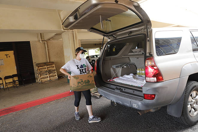 JAMM AQUINO / JAQUINO@STARADVERTISER.COM
                                Jay Purvis, an Aloha Harvest staff member, loads food into a waiting vehicle during a food drive at Aiea High School on Friday. The shut down of tourism in Hawaii in response to the coronavirus pandemic has crippled the state’s economy, leaving tens of thousands of residents in need of food assistance.