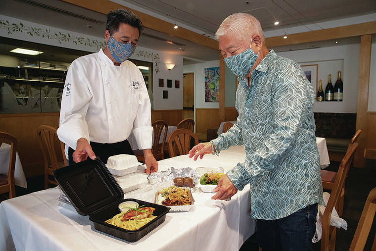 GEORGE F. LEE / GLEE@STARADVERTISER.COM
                                Amos Kotomori picks up his takeout order from chef Russell Siu at 3660 on the Rise. Kotomori said he wants to support restaurants, but doesn’t feel comfortable sitting down for a dine-in meal.