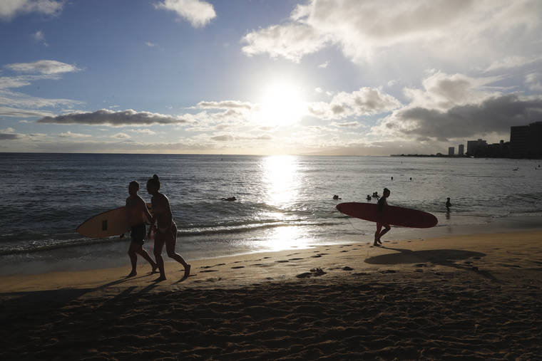 JAMM AQUINO / AUG. 6
                                Surfers exit the ocean near the Kapahulu groin in Waikiki. The surge in COVID-19 cases prompted the closure of beaches and city parks on Oahu to curb the spread of the virus.