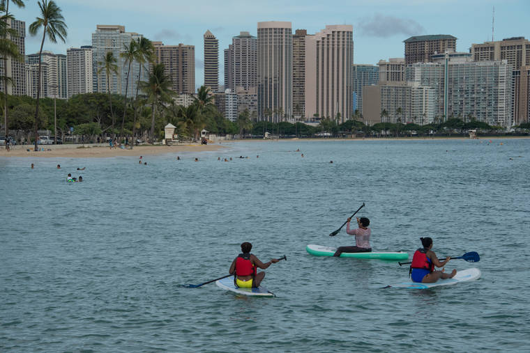CRAIG T. KOJIMA / CKOJIMA@STARADVERTISER.COM
                                County and state beach parks remain off-limits on Oahu, but people are allowed to cross beach parks to engage in ocean activities. Paddle boarders enjoy the water on the Ewa side of Ala Moana Beach Park on Friday.