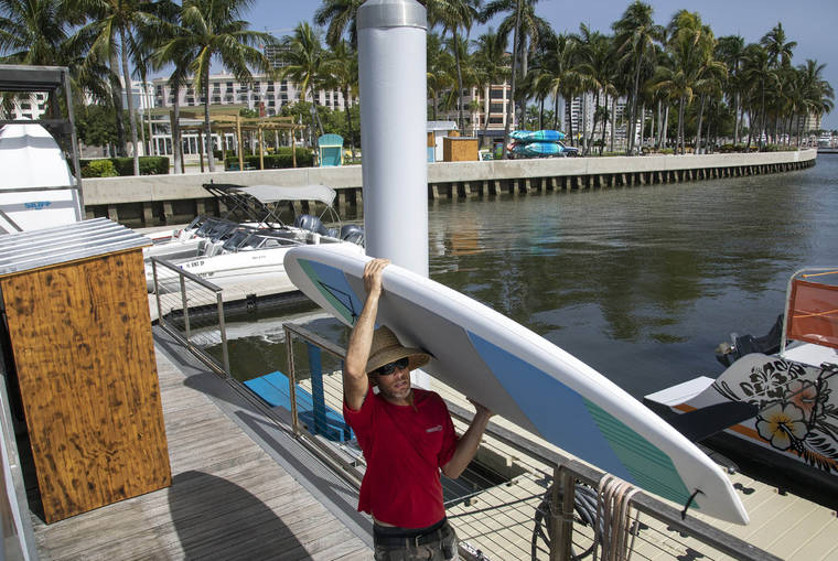 LANNIS WATERS/THE PALM BEACH POST VIA AP
                                Erin Flaherty removes paddle-boards from the city docks in West Palm Beach, Fla., in advance of Hurricane Isaias. Forecasters have declared a hurricane watch for parts of the Florida coastline as Hurricane Isaias drenches the Bahamas on a track for the U.S. East Coast.