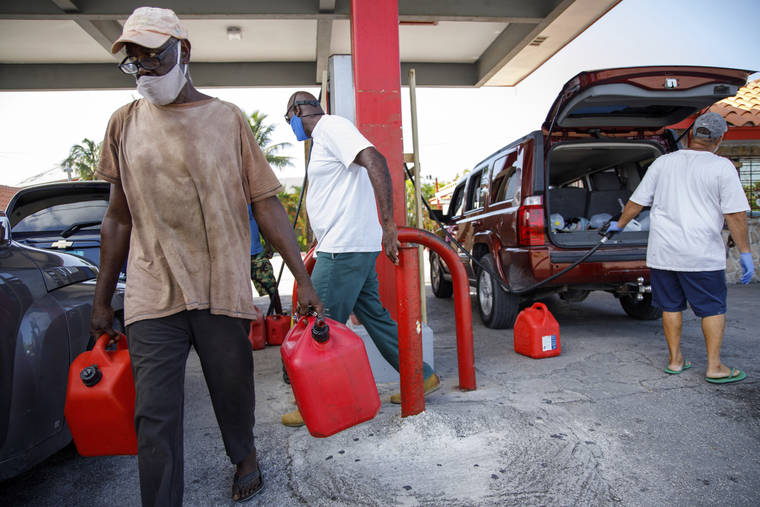 AP
                                A resident walks with containers filled with gasoline at Cooper’s gas station before the arrival of Hurricane Isaias in Freeport, Grand Bahama, Bahamas.