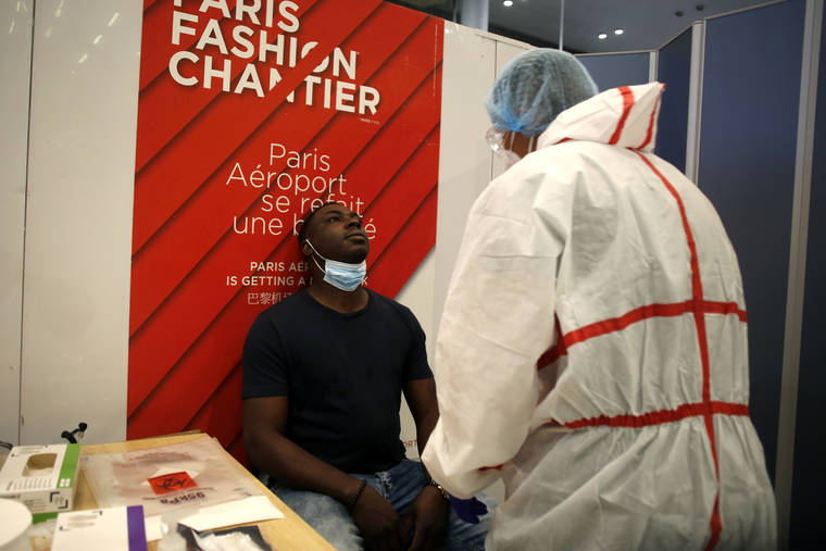 ASSOCIATED PRESS
                                A health worker is going to collect a nasal swab sample for COVID-19 test, at the Roissy Charles de Gaulle airport, outside Paris. Travelers entering France from 16 countries where the coronavirus is circulating widely are having to undergo virus tests upon arrival at French airports and ports.