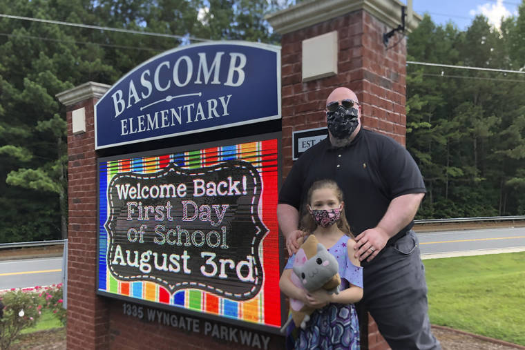 ASSOCIATED PRESS
                                John Barrett and his daughter Autumn pose for photos outside Bascomb Elementary School in Woodstock, Ga., on Thursday. Barrett says he will educate his daughter virtually and keep her out of in-person classes in Cherokee County schools, even though he’s worried she will fall behind on her special education plans, because of concerns about COVID-19’s spread. Cherokee County, near Atlanta, is one of many districts nationwide that gave parents a choice between in-person and all-online classes this fall.