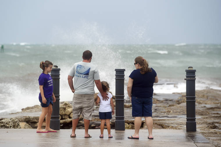 Elizabeth Whittemore (from left), along with her father James, sister Jordan and mother Susan, stand at the end of the South Jetty in Fort Pierce on Sunday, Aug. 2, 2020, watch the waves crash over the rocks brought by the high winds of Tropical Storm Isaias churning off the coast. (Patrick Dove/TCPalm.com via AP)