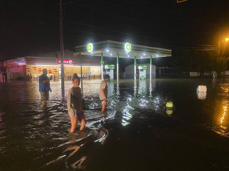 ASSOCIATED PRESS
                                People walk on the flooded Sea Mountain Highway in North Myrtle Beach, S.C., as Isaias neared the Carolinas on Monday night. Isaias made landfall as a hurricane near Ocean Isle Beach, North Carolina late Monday, according to the National Hurricane Center.
