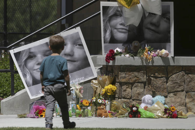 FILE - In this June 11, 2020, file photo, a boy looks at a memorial for Tylee Ryan, 17, and Joshua "JJ" Vallow, 7, at Porter Park in Rexburg, Idaho. An Idaho prosecutor is expected Monday, Aug. 3, 2020, to begin sketching out his case against an Idaho couple at the center of a bizarre missing children's case that ended in tragedy when their bodies were found buried on a rural eastern Idaho property earlier this year. (John Roark/The Idaho Post-Register via AP, File)
