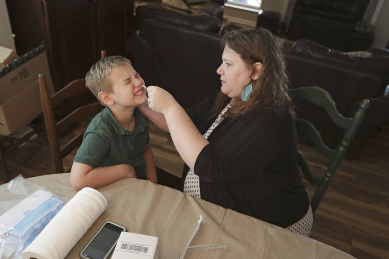 ASSOCIATED PRESS
                                Mendy McNulty swabs the nose of her son, Andrew, 7, on July 28 in their home in Mount Juliet, Tenn. Six thousand U.S. parents and kids are swabbing their noses twice a week to answer some of the most vexing mysteries about the coronavirus. The answers could help determine the safety of in-class education during the pandemic.