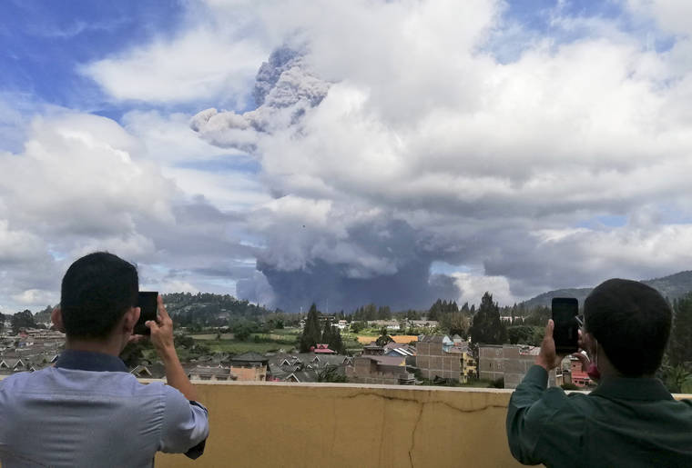 ASSOCIATED PRESS
                                Indonesian men use their mobile phones to take photos as Mount Sinabung spews volcanic materials into the air as it erupts, in Karo, North Sumatra, Indonesia, today. The rumbling volcano erupted today, sending a column of volcanic materials a few thousands meters into the sky. Sinabung is among more than 120 active volcanoes in Indonesia.