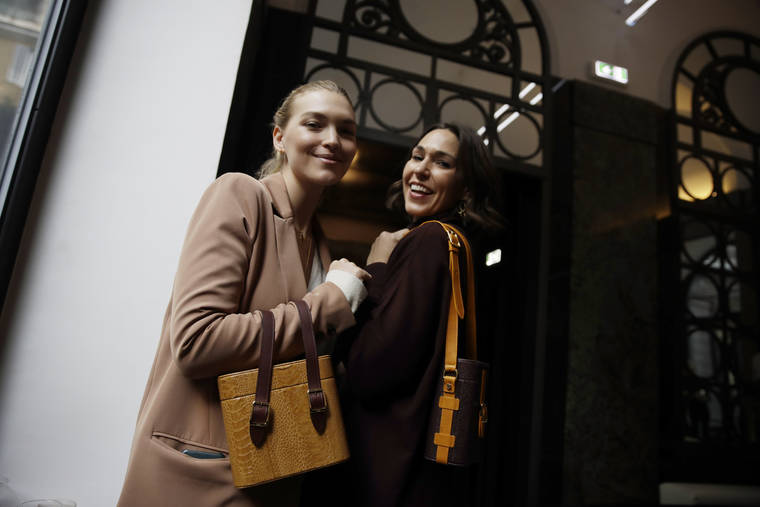 ASSOCIATED PRESS
                                In this 2019 file photo, model Arizona Muse, left, is flanked by designer and Officina del Poggio owner Allison Hoeltzel Savini as they present a creation of the Officina del Poggio women’s Fall-Winter 2019-2020 collection, in Milan, Italy. The United States’ fumbling response to the pandemic is casting doubt on its economic prospects and making it one of the chief risks that could undermine the rebound. Officina del Poggio sells 60% its vintage motorcycle-inspired satchels to U.S. customers.