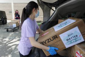 ASSOCIATED PRESS
                                Valerie Xu, 15, carried boxes of masks to a waiting cart held by UT Southwestern Medical Center employee, Cindy Levy, in Dallas, June 5. Xu raised the funds to buy the masks and make the donation to the hospital.