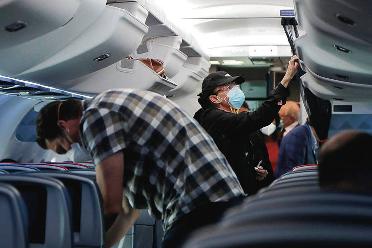 ASSOCIATED PRESS
                                Travelers wear masks for protection from the coronavirus as they settle into their seats on a Delta Airlines flight before takeoff from Ronald Reagan Washington National Airport on May 28 Arlington, Va.