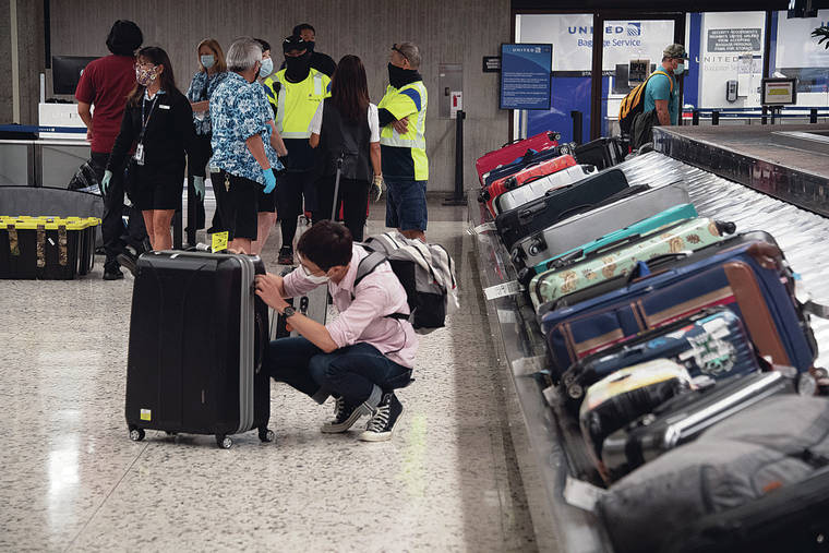 CRAIG T. KOJIMA / AUG. 4
                                Overall, visitor arrivals to Hawaii dropped about 65% in the first seven months of this year. Above, a traveler picked up his luggage after arriving at Daniel K. Inouye International Airport.