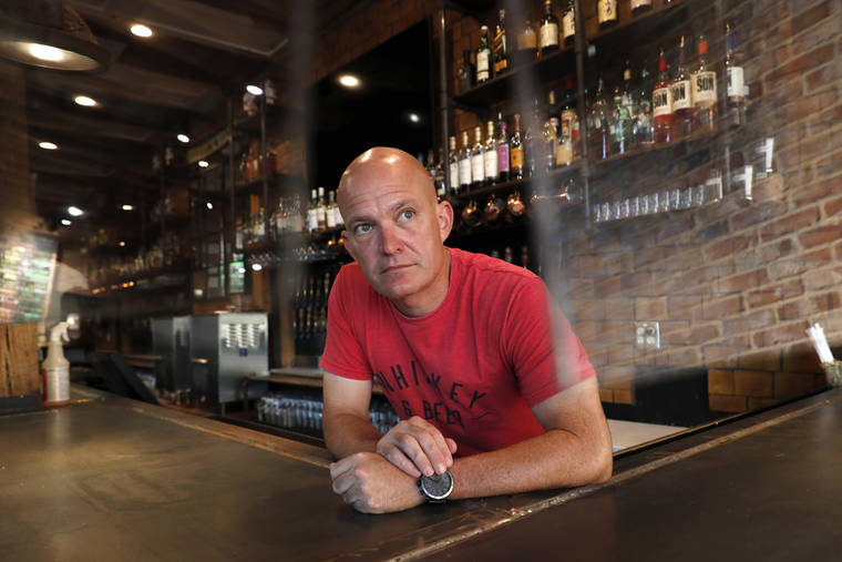 ASSOCIATED PRESS
                                Jeff Brightwell, owner of Dot’s Hop House,was framed between protective shielding placed over the bar as he posed for a photo at his establishment in the Deep Ellum entertainment district in Dallas, Aug. 20.