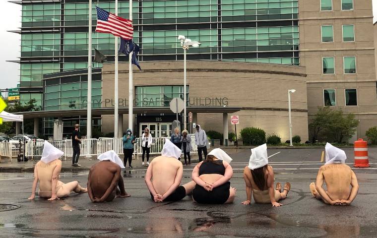 TRACY SCHUHMACHER/DEMOCRAT & CHRONICLE VIA ASSOCIATED PRESS
                                Naked protesters, wearing “spit hoods” in reference to the killing of Daniel Prude, demonstrated outside Rochester’s Public Safety Building in Rochester, N.Y..