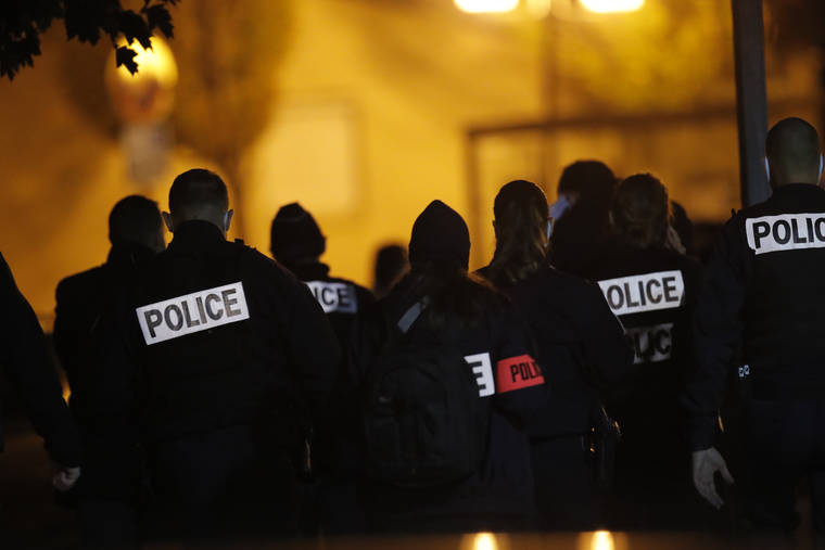 ASSOCIATED PRESS
                                French police officers gather outside a high school after a history teacher who opened a discussion with students on caricatures of Islam’s Prophet Muhammad was beheaded Friday in Conflans-Saint-Honorine, north of Paris. Police have shot the suspected killer dead.