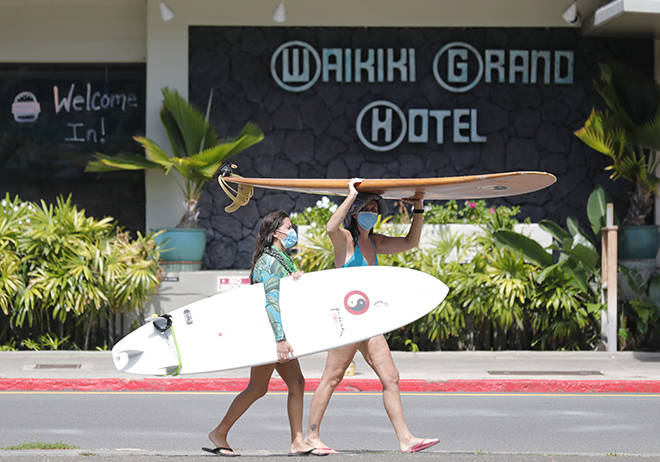 JAMM AQUINO / JAQUINO@STARADVERTISER@COM
                                Surfers wear masks while walking with their boards along Kapahulu Avenue on Oct. 19 in Waikiki.