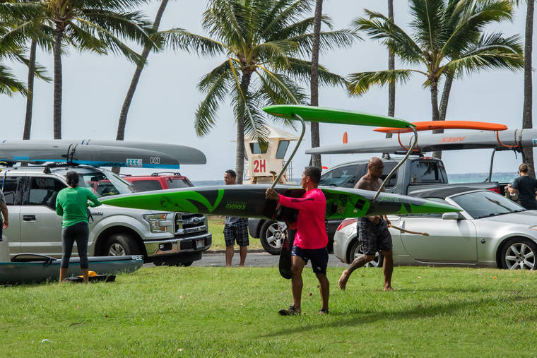CRAIG T. KOJIMA / NOV. 22
                                Travis Kamakele transports his canoe to a waiting truck after making a run from Hawaii Kai to Kaimana Beach.