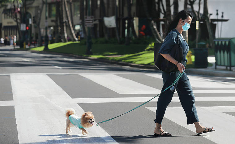 JAMM AQUINO / JAQUINO@STARADVERTISER.COM
                                A woman wore a face mask as she and her dog crossed Kalakaua Avenue on Tuesday in Waikiki.