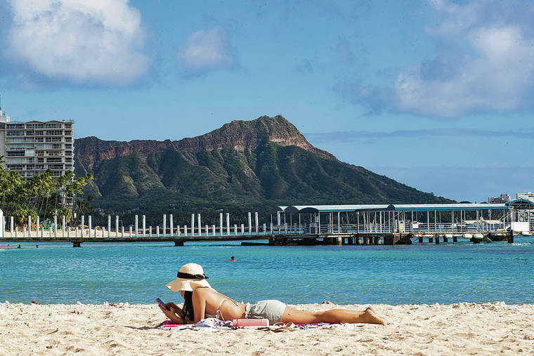 CINDY ELLEN RUSSELL / NOVEMBER 19
                                A beachgoer checked her phone while sunning in Waikiki.