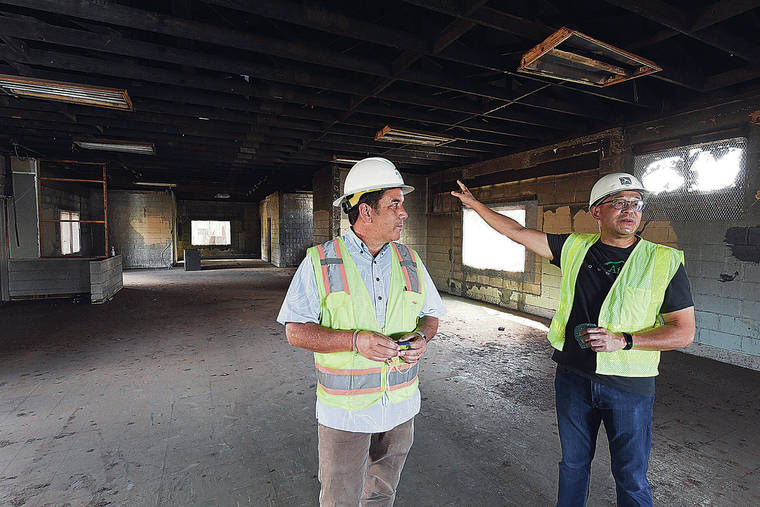 CRAIG T. KOJIMA / CKOJIMA@STARADVERTISER.COM
                                Chad Johnston, left, building captain for the community building, and Alan Ong, building captain for the overall site, show the structure that will become the kauhale community building. It will contain bathrooms, showers, a lounge, medical treatment facilities and a pavilion.
