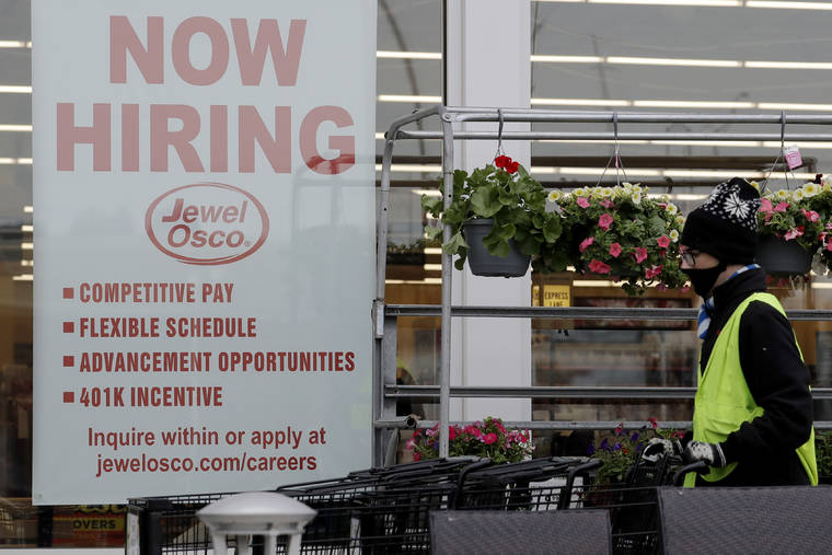ASSOCIATED PRESS
                                A man pushes carts as a hiring sign shows at a Jewel Osco grocery store in Deerfield, Ill., Thursday.
