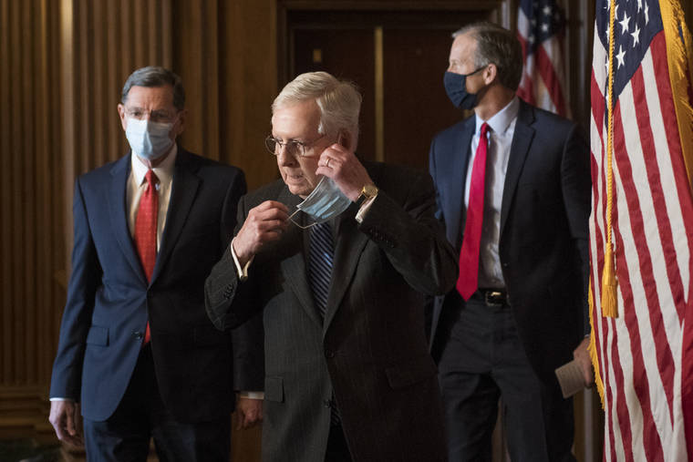 ROD LAMKEY/POOL VIA AP / DEC. 15
                                Senate Majority Leader Mitch McConnell of Ky., removes his face mask as he arrives with Sen. John Barrasso, R-Wyo., left, and John Thune, R-S.D., right, for a news conference with other Senate Republicans on Capitol Hill in Washington.