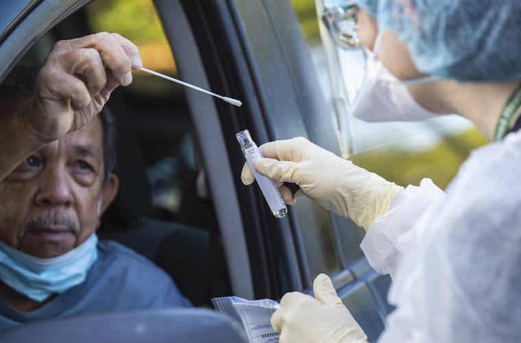 CINDY ELLEN RUSSELL / CRUSSELL@STARADVERTISER.COM
                                Phillip Delos Santos returns a nasal swab to a vial held by health care worker Leanne Jones during a drive-thru COVID-19 testing at Wahiawa Health on Sunday.