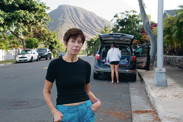 CRAIG T. KOJIMA / CKOJIMA@STARADVERTISER.COM
                                Hawaii Kai resident Jennifer Taylor stood on Nawiliwili Street on Thursday. Behind her Hanauma Bay visitors parked and prepared to hike to the entrance. Traffic has increased in the area since the nature preserve’s reopening.