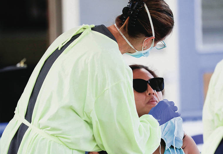 JAMM AQUINO / JAQUINO@STARADVERTISER.COM
                                Project Vision Hawaii RN Toni Floerke, left, administered a COVID-19 PCR test to Honolulu resident Kristine San Diego on Sunday at St. Theresa Co-Cathedral church in Kalihi.