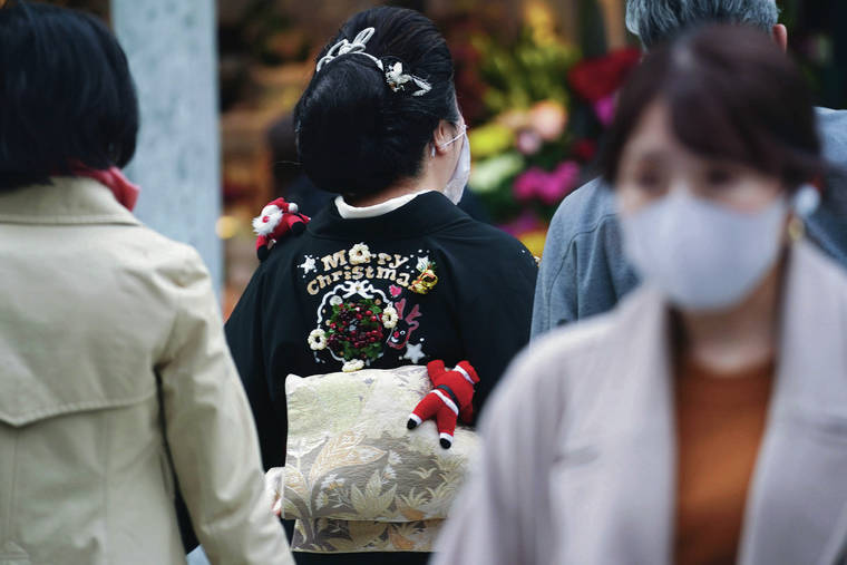 ASSOCIATED PRESS
                                <strong>A bit of cheer</strong>: A woman with festive touches on her traditional kimono walks among masked shoppers in the Ginza district in Tokyo. The whimsical sight is stark contrast to a steady rise of COVID-19 cases in Japan.