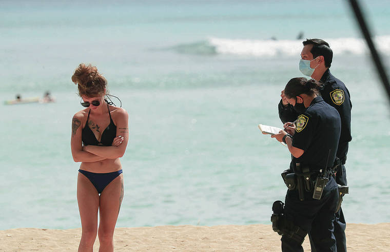JAMM AQUINO / SEPT. 8
                                Honolulu police issue a citation to a woman on the beach near the Duke Kahanamoku statue in Waikiki. Oahu’s stay-at-home, work-from-home order limited many outdoor activities.