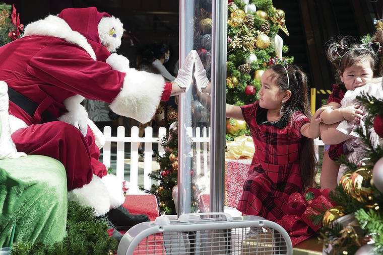 GEORGE F. LEE / NOV. 21
                                Five-year-old Ria Mayekawa reaches out to touch Santa Claus’ hand through plexiglass prior to having her picture taken with him and her sister Mika, 1, right, at Windward Mall in Kaneohe.
