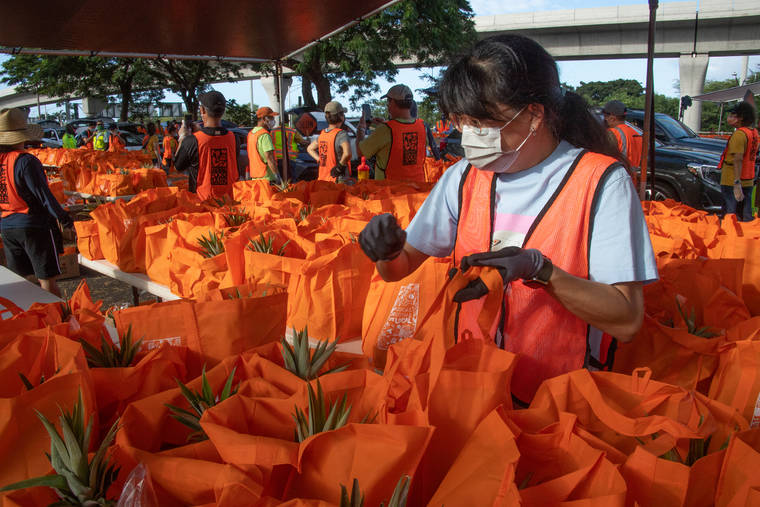 CRAIG T. KOJIMA / CKOJIMA@STARADVERTISER.COM
                                Volunteer Roberta Hsu packs bags of groceries for distribution on Friday at Aloha Stadium.