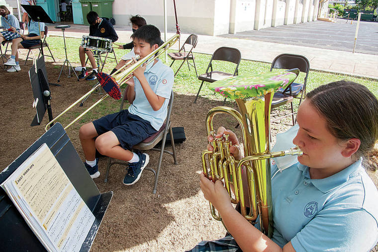 CRAIG T. KOJIMA/CKOJIMA@STARADVERTISER.COM
                                Eighth grader Travis Ouchi and seventh grader Mahina Williams use a covering over their instruments at Mary, Star of the Sea School.