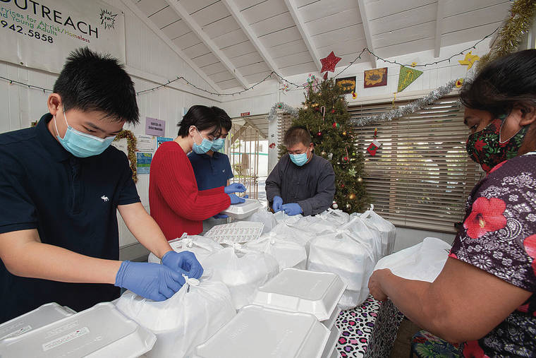 CINDY ELLEN RUSSELL / CRUSSELL@STARADVERTISER.COM
                                Victor Tan and his family, along with Tracey Ngiratebl, right, prepared 100 Christmas meals that were headed to the Youth Outreach in Waikiki. Above, stickers with a holiday message were placed on the meal boxes.