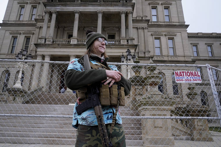 ASSOCIATED PRESS
                                Timothy Teagan, a member of the Boogaloo Bois movement, stands with his rifle outside the state capitol in Lansing, Mich., today.
