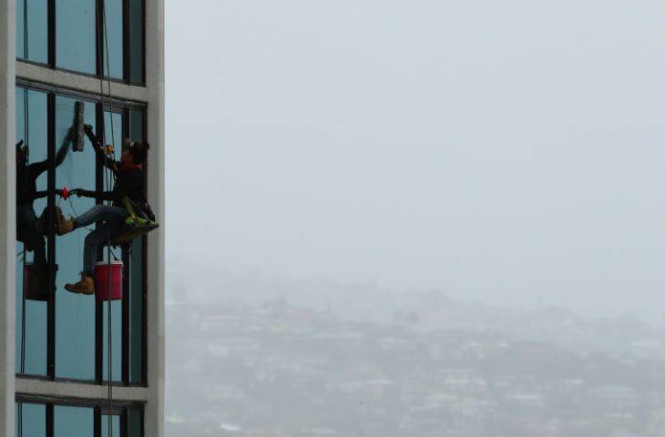 JAMM AQUINO / JAQUINO@STARADVERTISER.COM
                                A window washer worked with Kaimuki in the background barely visible in the rain today.